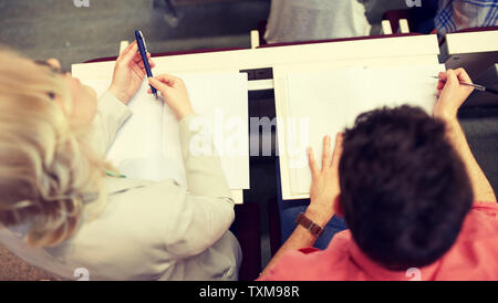 students with notebooks at exam or lecture Stock Photo