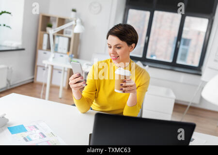 happy woman with coffee using smartphone at office Stock Photo