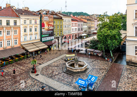 Lviv, Ukraine - July 31, 2018: Aerial high angle bird's eye view of historic Ukrainian city in old town market square with cafe restaurant water fount Stock Photo