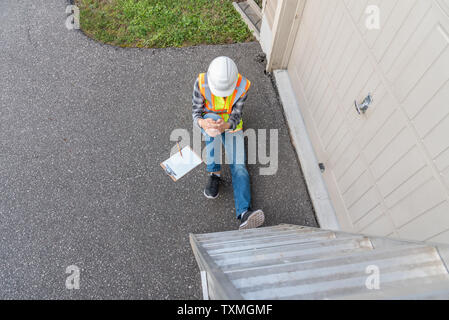 Injured architect sitting on the ground after having fallen off a ladder. Stock Photo