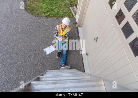 Injured architect sitting on the ground after having fallen off a ladder. Stock Photo
