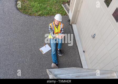 Injured architect sitting on the ground after having fallen off a ladder. Stock Photo