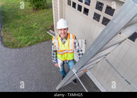 Young male architect standing on a ladder and dressed in safety gear. Stock Photo