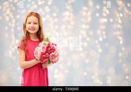 happy red haired girl with flowers over lights Stock Photo
