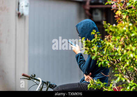 Kyoto, Japan - April 10, 2019: Takase river canal in residential neighborhood with man on bicycle and phone with hood by building Stock Photo