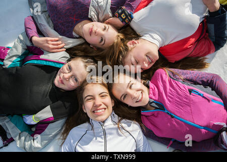 Five teenage girl skiers lying in a circle in snow, overhead portrait, Tyrol, Styria, Austria