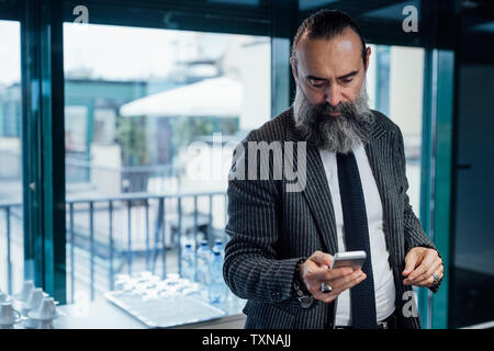Businessman using smartphone in office Stock Photo