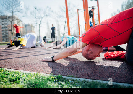 Calisthenics class at outdoor gym, man and women practicing yoga position Stock Photo