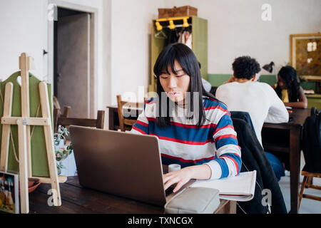 Young businesswoman remote working on laptop at cafe table Stock Photo