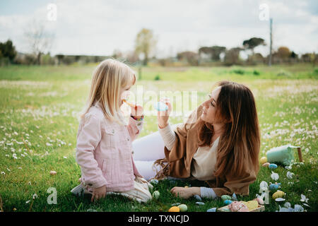Mother and daughter relaxing in wildflower field after easter egg hunt, Arezzo, Tuscany, Italy Stock Photo