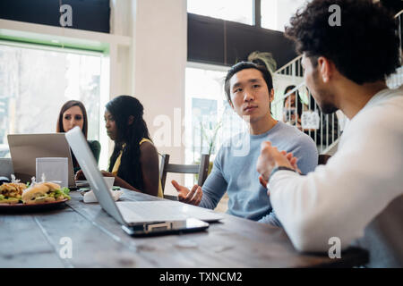 Young businessmen having discussion at cafe table Stock Photo