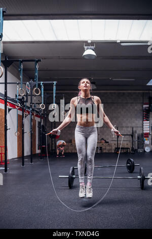 Young woman in gym skipping, full length Stock Photo