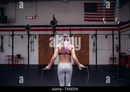Young woman training, holding skipping rope in gym, rear view Stock Photo