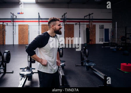 Young bearded man training, standing with hands on hips in gym Stock Photo