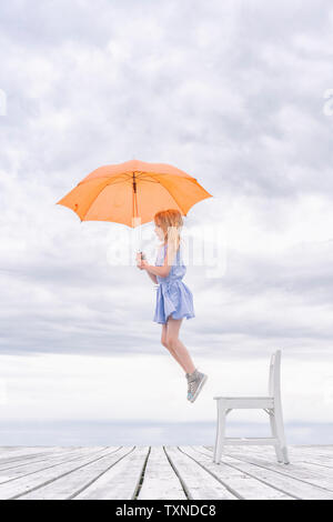 Girl being lifted off her chair by umbrella