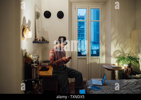 Bearded young man using smartphone on bedroom table Stock Photo
