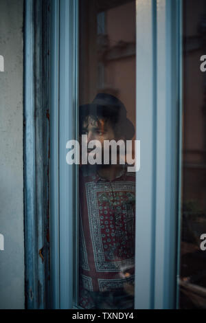Bearded young man in deep thought by window Stock Photo