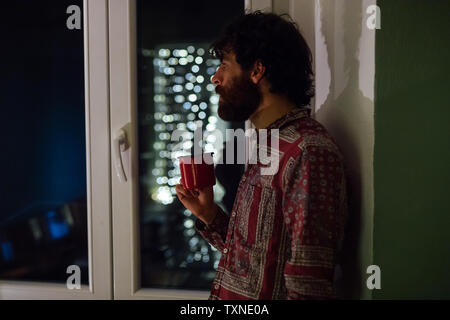 Bearded young man in deep thought by window Stock Photo