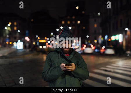 Bearded young man using smartphone on street Stock Photo