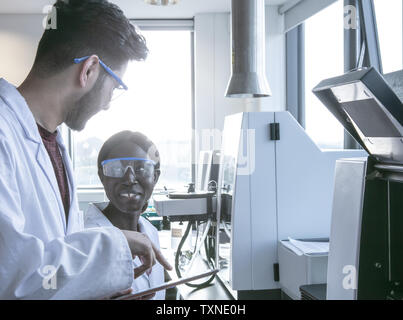Young female and male scientists using digital tablet and having discussion in laboratory Stock Photo