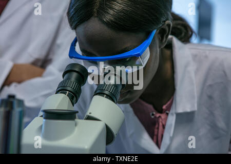 Young female scientist looking through microscope in laboratory, close up Stock Photo