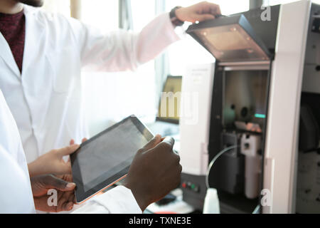 Young female and male scientists using digital tablet in laboratory, mid section Stock Photo