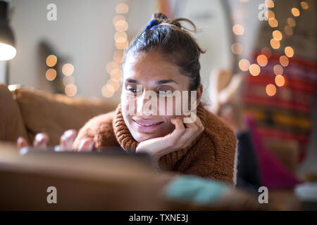Young woman lying on living room sofa looking at laptop, close up Stock Photo