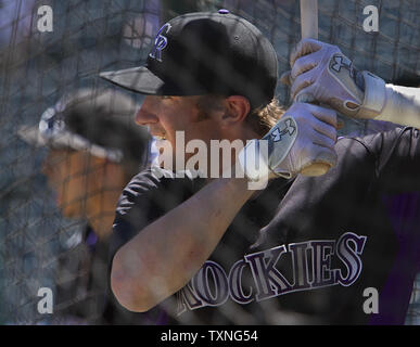 Colorado Rockies' Charlie Blackmon, left, shows to trainer Scott Gehret  where a foul ball hit his batting helmet as he stood in the on-deck circle,  during the third inning of the team's