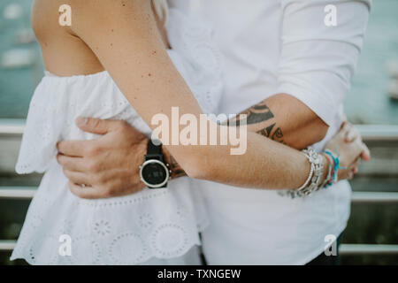 Romantic mid adult couple hugging on lakeside, mid section Stock Photo