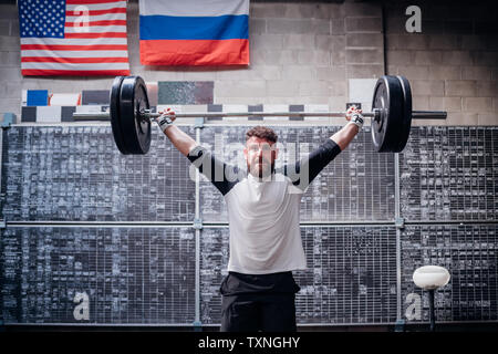 Young man lifting barbell in gym Stock Photo
