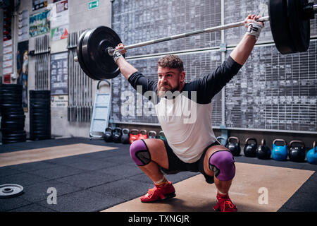 Young man lifting barbell in gym Stock Photo