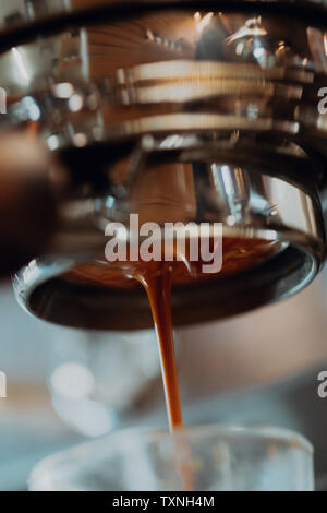 Fresh coffee pouring from coffee machine into drinking glass in cafe, close up Stock Photo