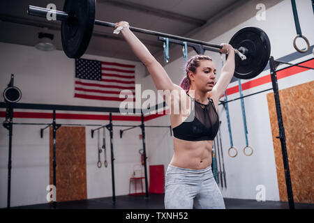 Young woman lifting barbell in gym Stock Photo