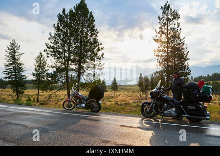 Senior male motorcyclist on rural roadside with motorbike, Dawson Creek, Canada Stock Photo