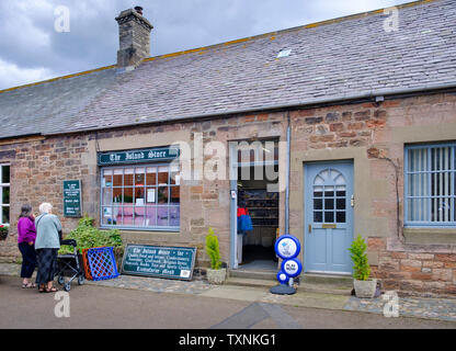 Two elderly women look at shop window of a village shop called the  Island Store a general store on Lindisfarne Holy Island Stock Photo