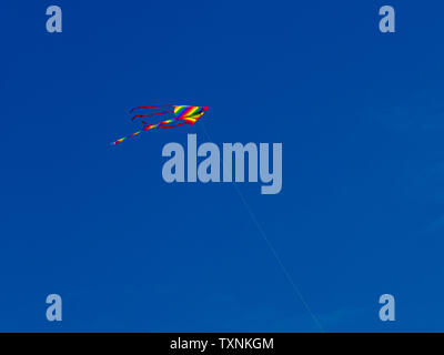 A kite flying in the air against a beautiful blue summer sky. Stock Photo