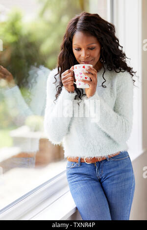 Ethnic girl relaxing with warm drink Stock Photo
