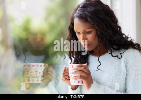 Ethnic woman looking sad sat in a window Stock Photo