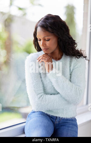 Ethnic woman looking sad sat in a window Stock Photo