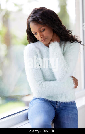 Ethnic woman looking sad sat in a window Stock Photo