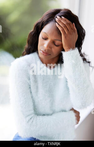 Ethnic woman looking sad sat in a window Stock Photo