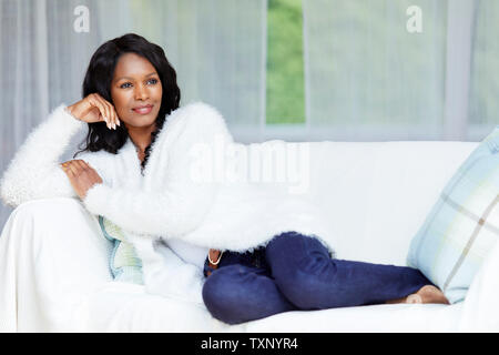 Ethnic woman sat relaxing on sofa Stock Photo