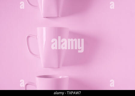 One singled out monochromatic pink coffee mug lined up in a row on pink background with blank empty room space for text, copy, or copyspace. Modern to Stock Photo