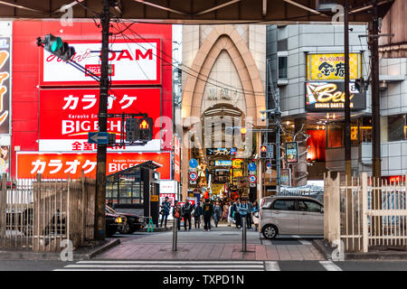 Osaka, Japan - April 13, 2019: Entrance to famous arcade street with people walking shopping by road traffic Stock Photo