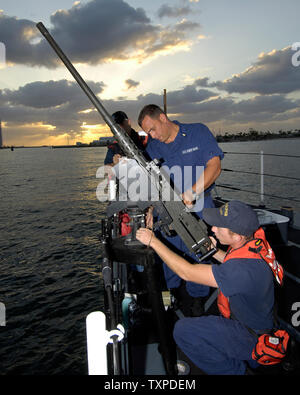 As the sun rises on the US Coast Guard Cutter 'Dolphin', Chief Tobin (c) and Seaman Carson (r) mount one of two 50 caliper machine guns. The US Coast Guard is providing security for the arrival of US and Canadian Naval vessels for 'Fleet Week USA' at Port Everglades in Ft. Lauderdale, Fla. on May 1, 2006. (UPI Photo/Joe Marino - Bill Cantrell) Stock Photo