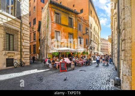 Tourists enjoy lunch on a summer day at an Italian sidewalk cafe restaurant in an alley near the historic center of Rome, Italy. Stock Photo