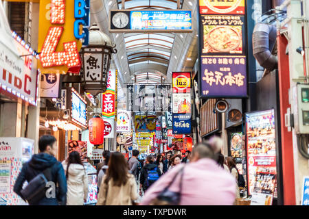 Osaka, Japan - April 13, 2019: Inside famous arcade street with people crowd walking shopping with many neon signs Stock Photo