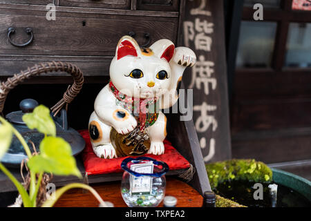 Osaka, Japan - April 13, 2019: Store display closeup from street road window with lucky cat neko paw and sign Stock Photo