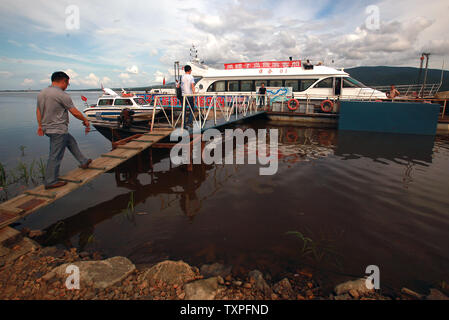 A Chinese tourist boat waits for passengers before heading up the Songhua River and its wetlands, which serves as a natural border between China and Russia (background), in Fuyuan, a frontier town in China's northern Heilongjiang Province on August 4, 2013.  Ecotourism has been part of household vocabularies in China for a decade, however experts believe that the concept still has a long way to go in China.  Most domestic tourists are more interested in sightseeing than promoting environmental programs and awareness, according to a study.     UPI/Stephen Shaver Stock Photo