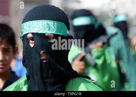 Masked members of Hamas' armed wing, Ezzedine al-Qassam Brigades, hold fake rifles and wear fake explosive belts during a rally in the Jabalya refugee camp in the southern Gaza Strip, on October 24, 2003. Palestinian militant groups Hamas and Islamic Jihad jointly claimed responsibility today for an overnight attack on a Jewish settlement in Gaza that left three Israelis and one of the gunmen dead. (UPI/Ismael Mohammad) Stock Photo